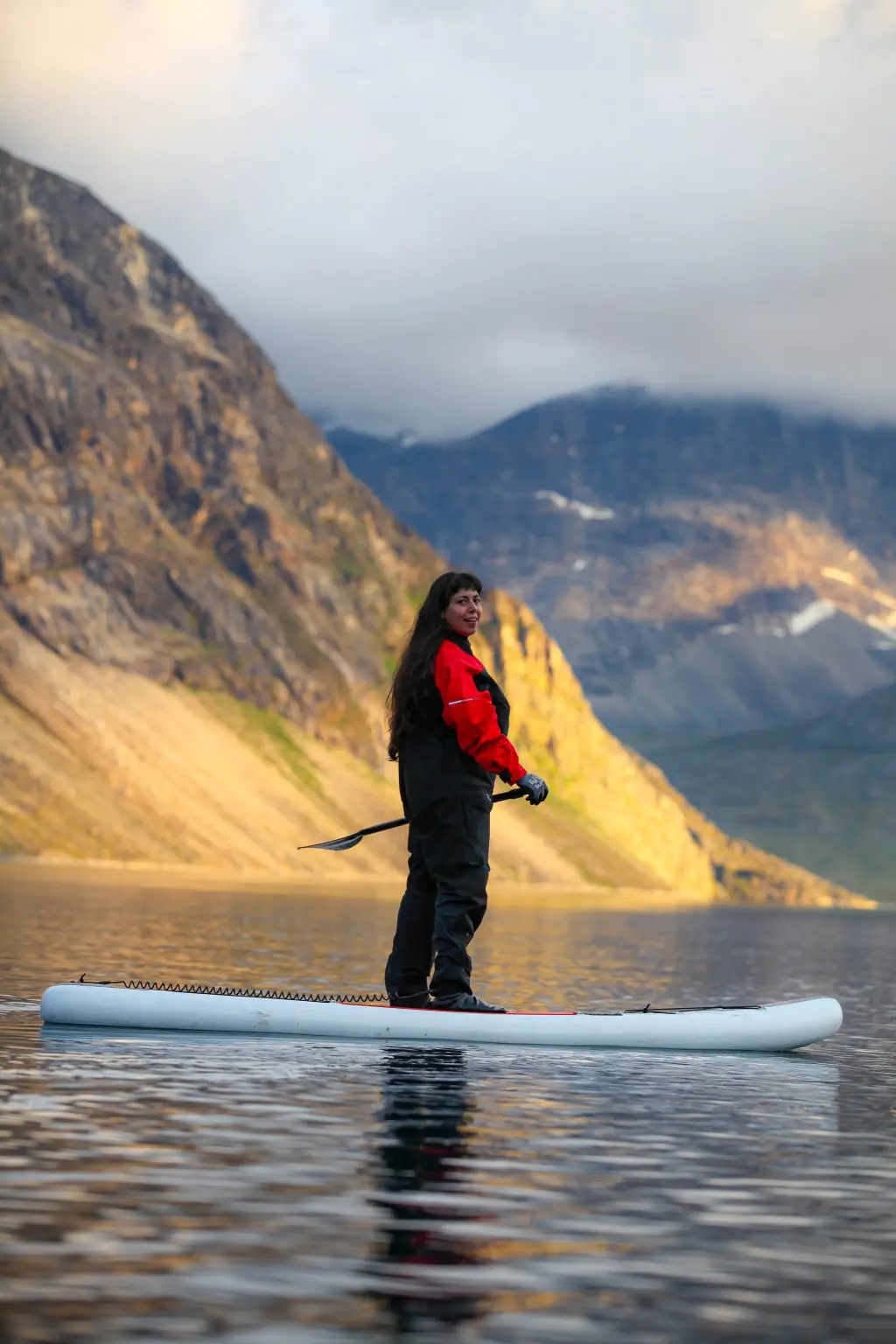 a woman paddleboarding in Greenland